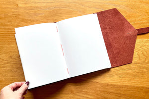 Leather journal / notebook with unlined plain blank pages which lay flat on a desk, bound by hand in oxblood with orange stitching