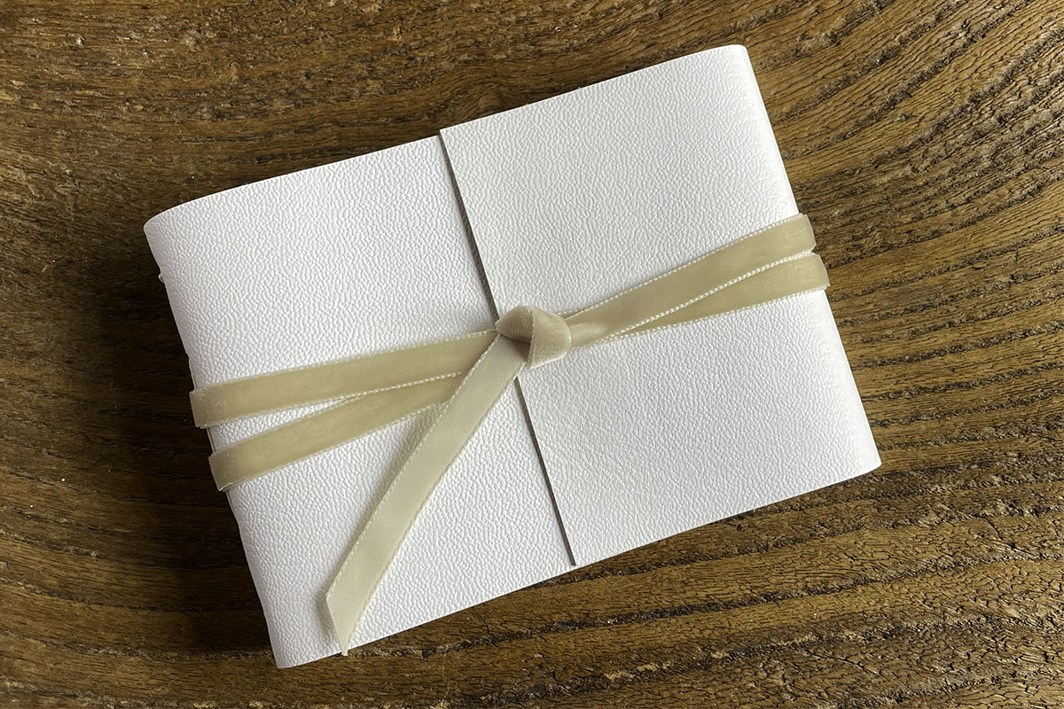 Lay flat Medieval binding Wedding Guest Book bound in white leather with Natural details in linen and velvet