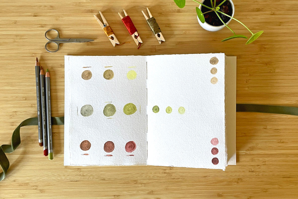 Colour swatches in pencil and wash on open pages of medium Wabi Sabi cotton rag sketchbook, an option for enhanced pages in an art journal with prompts.