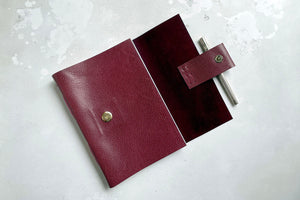 Extra wide penholder fob lies open to show magnetic snap that keeps this handmade leather journal closed for travel