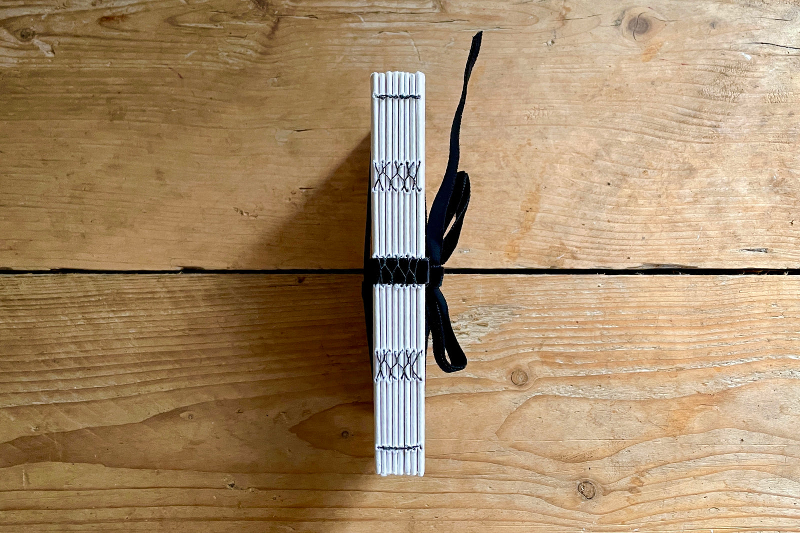 Lay flat sketchbook with 210gsm handmade cotton rag paper sized for wet and dry art work with black velvet ribbon.