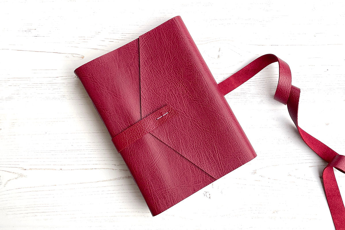 A5 Art Sketchbook bound in Crimson Red Leather with Lilac stitching, strap and envelope cover flap.