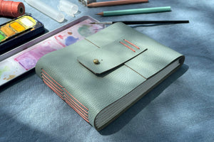 Longstitch exposed spine stitching in Coral linen thread on a Duck Egg leather watercolour sketchbook