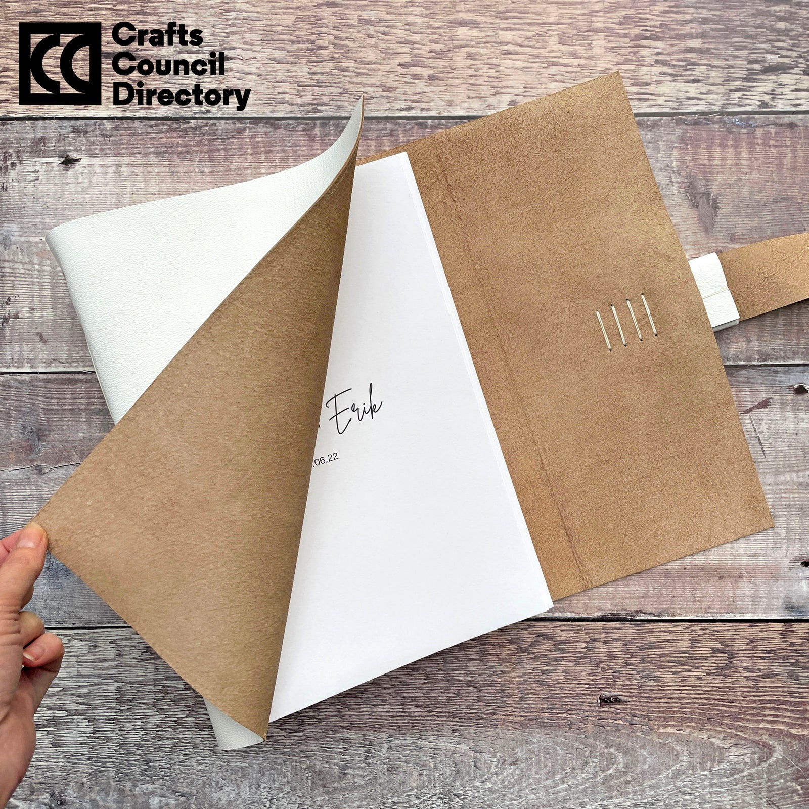 Personalised Wedding Guest Book handmade in white leather with bespoke, custom text on the titlepage, revealed by bookbinder turning the soft cover. The Crafts Council Directory membership logo appears in the top left corner. 