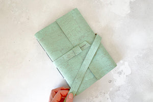 Sketchbook held securely closed for travel or archiving with a strap and soft buckles