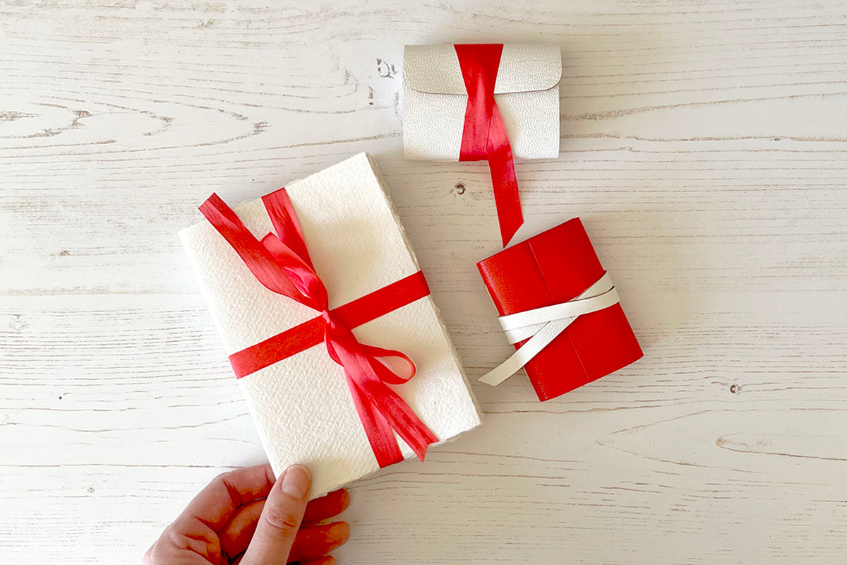 Miniature Journal bound in white leather with red silk, held by bookbinder.