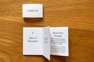 Artist's Book of journaling prompts with open folded Leporello pages and belly band