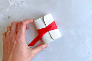 Miniature Journal bound in white leather with red silk, held by bookbinder.