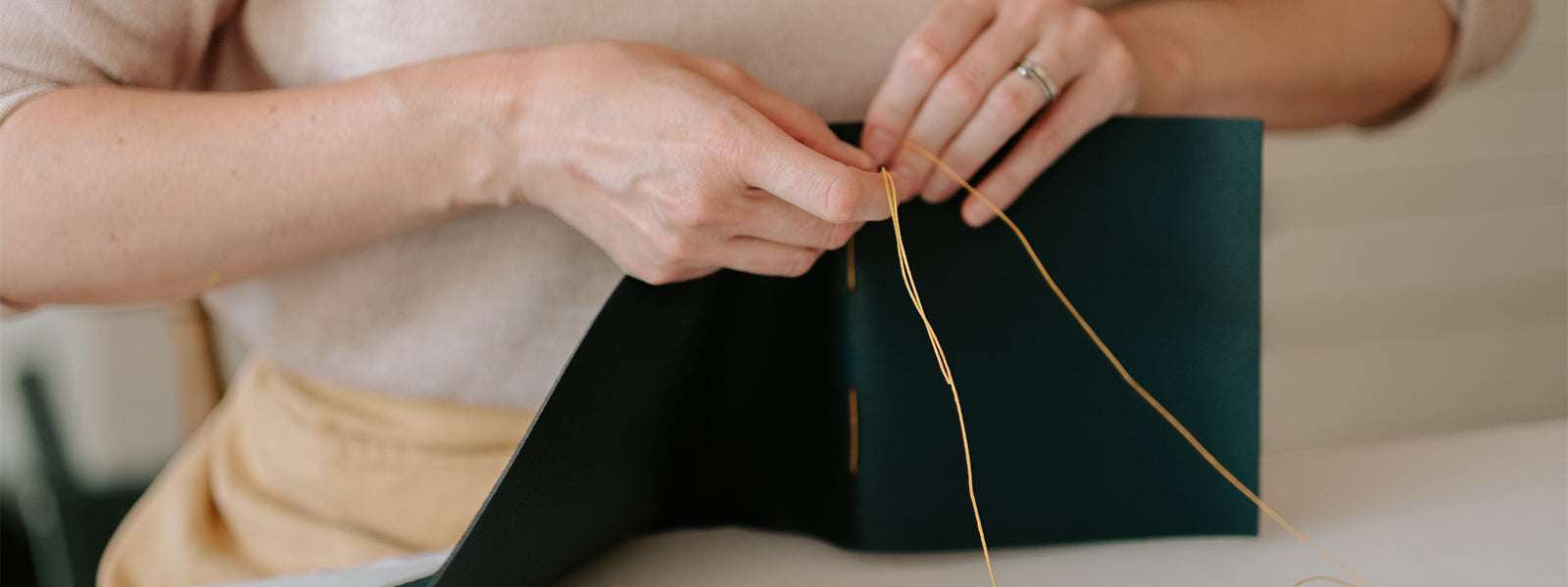 Dorset bookbinder Susan Green of Bound by hand stitches a navy blue handmade leather journal