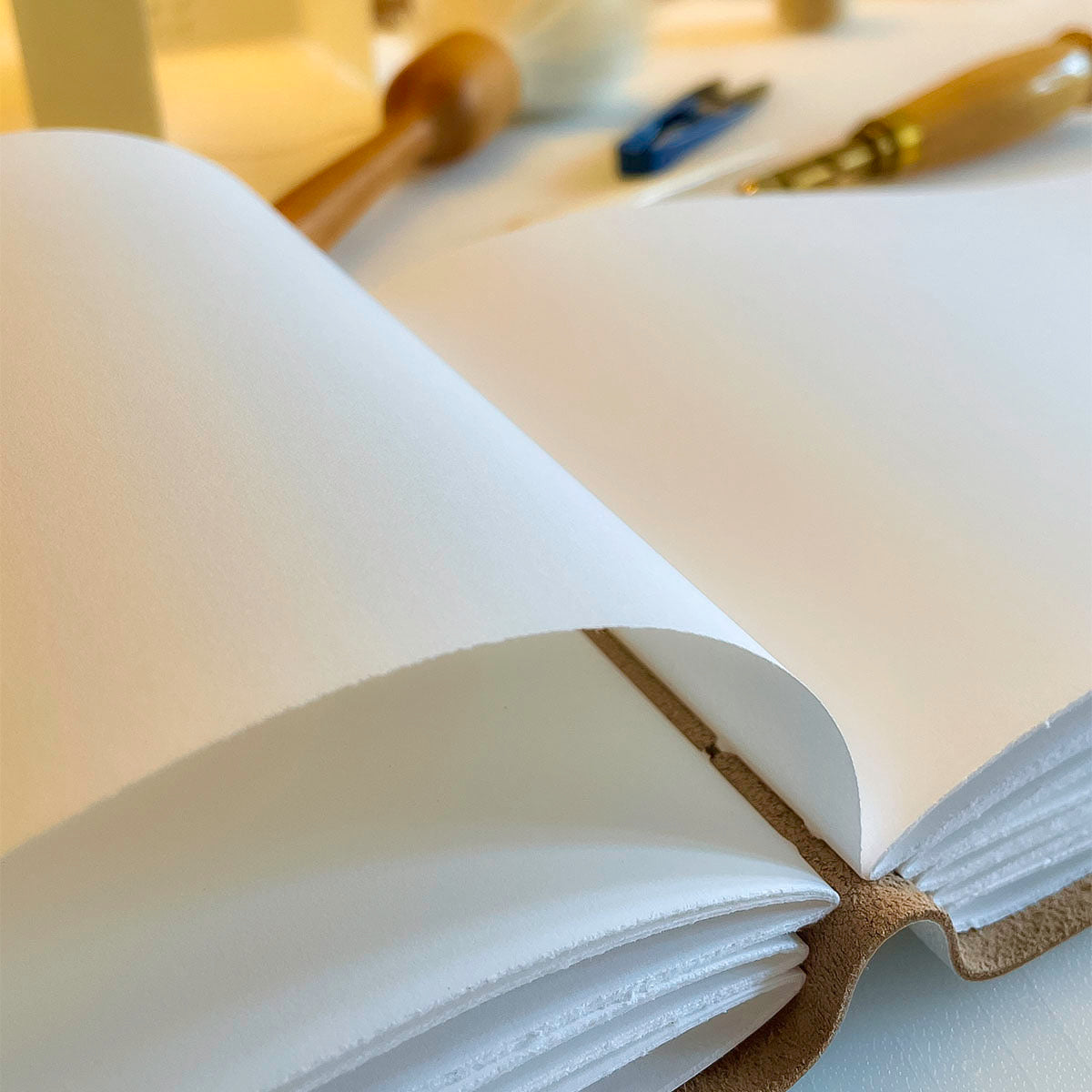 A4 wedding guest book handmade in white leather is closed with a luxurious woven silk ribbon when not in use.