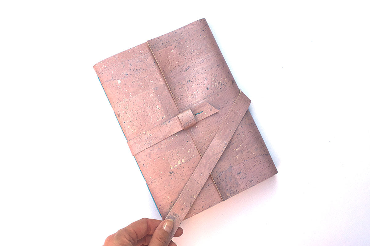 Hand holds strap of Cork Sketchbook in Rose Gold cork textile