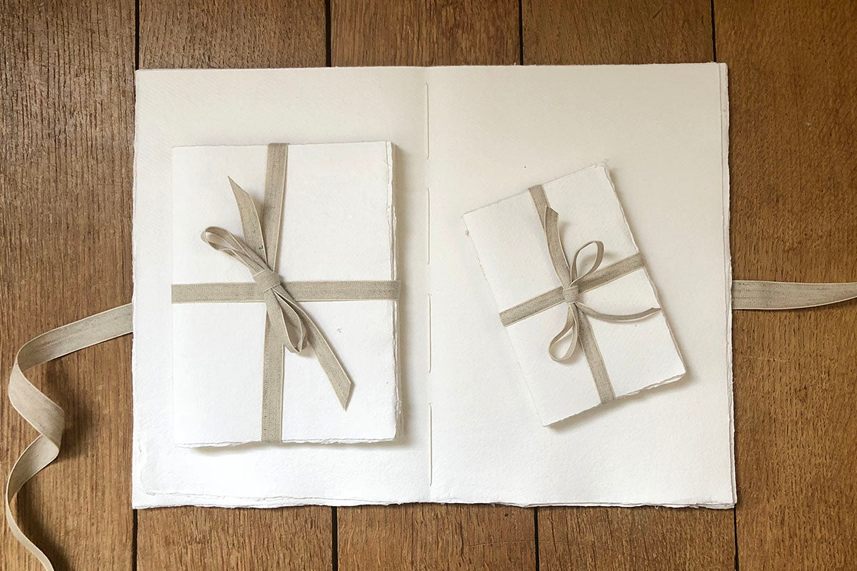 Handmade cotton rag sketchbook with exposed spine bound by artisan bookbinder Susan Green, who ties its linen ribbon. 