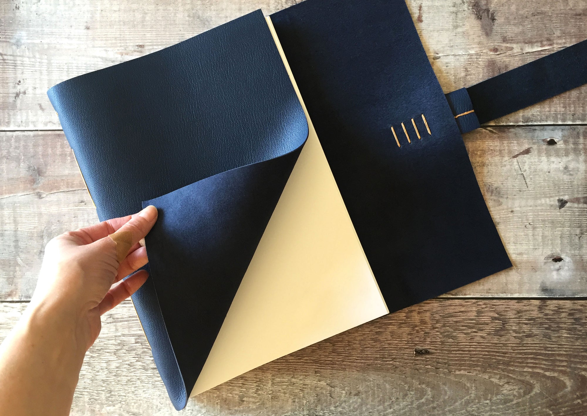 A4 Leather Journal in Navy Blue, hand turns softcover to titlepage