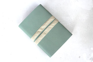 Natural unbleached woven linen ribbon keeps leather sketchbook closed.