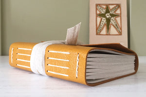 Leather Sketchbook in Mustard Yellow, Longstitch binding with handmade embroidery star in background